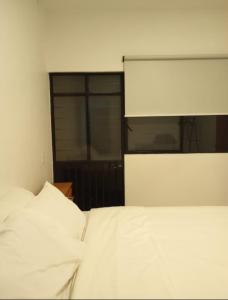 ein Schlafzimmer mit einem weißen Bett und einem Fenster in der Unterkunft Orizaba Suites in Río Blanco
