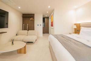 Habitación de hotel con cama y sala de estar. en Haeilri Pool&SPA Hotel en Seogwipo