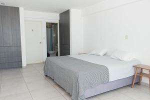 a white bedroom with a bed and a table at Amplio Duplex Huanchaco - Vista al Mar y Ascensor in Trujillo