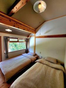 a bedroom with two beds and a window at 旧と新の出会いー琉球古民家 蒼 in Motobu