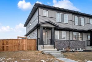 una casa gris con una valla de madera delante de ella en Modern & Spacious Guest Suite, en Calgary