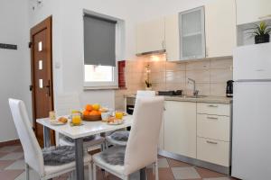 a kitchen with a white table and white cabinets at Ibeach By Rok Apartment in Novigrad Dalmatia
