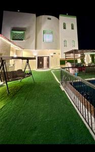 una casa con erba verde nel cortile di فيلا الوريك Villa Al Warik a Umm Lajj