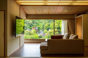 a living room with a couch and a large window at Hakone Yumoto Onsen Hotel Kajikaso in Hakone