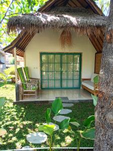 龍目島的住宿－Bintang Tiga Bungalows Gili Air，草屋顶,长凳和树的房子