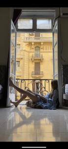OH! Cairo Pharaoh Hostel في القاهرة: امرأة ملقاة على الأرض أمام نافذة