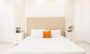 una camera con un letto bianco e un cuscino arancione di Brunei Hotel Boutique a Boca Chica
