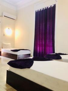 カイロにあるOH! Cairo Pharaoh Hostelの紫色のカーテンが備わるドミトリールームのベッド2台
