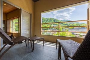 einen Balkon mit Stühlen und einem großen Fenster in der Unterkunft Hakone Yumoto Onsen Hotel Kajikaso in Hakone