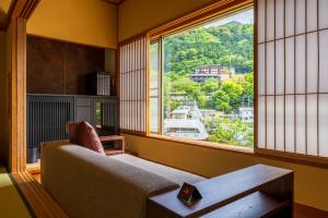 a living room with a couch and a large window at Hakone Yumoto Onsen Hotel Kajikaso in Hakone