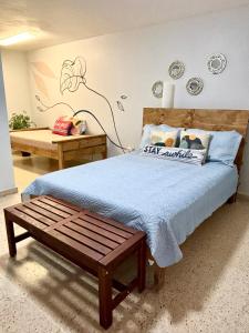 um quarto com uma cama com um cobertor azul e um banco em Bee Inn Puerto Rico Charming Urban Apartment in San Juan em San Juan
