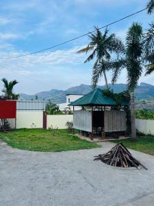 ein Gebäude mit einem grünen Dach und einem Stapel Stöcke in der Unterkunft Kadampil Bliss in Maraiyūr