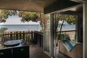 Golden Bay Holiday Park في Onekaka: منزل مع شرفة مطلة على الشاطئ