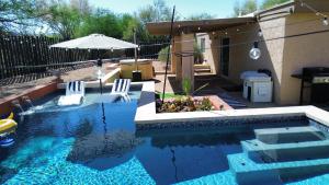 una piscina con 2 sillas y una sombrilla en Stylish Fountain Hills gem with game room, en Fountain Hills