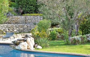 a pool with a chair next to a stone wall at Mas Anastasia in Les Baux-de-Provence