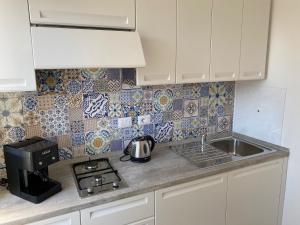 a kitchen with white cabinets and a sink and a stove at B&B La Lingua in Procida