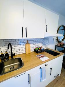 a kitchen with white cabinets and a sink at Stylish tiny home in Melton west in Melton
