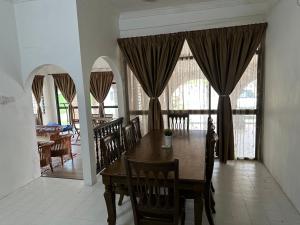 a dining room with a table and chairs and windows at Mawar 23 Chendering with Private Pool in Kuala Terengganu
