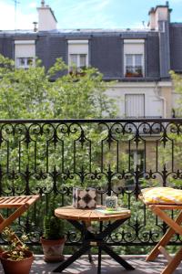 Charmant appartement avec balcon prés sacré cœur في باريس: طاولة على شرفة بجوار سياج
