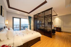 a bedroom with a large bed and a balcony at Eco Lux Riverside Hotel & Spa in Hoi An