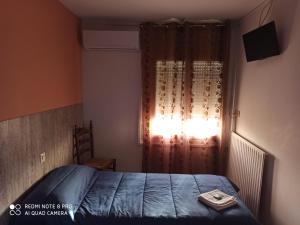 um quarto com uma cama azul e uma janela em Hostal Galicia em Figueres