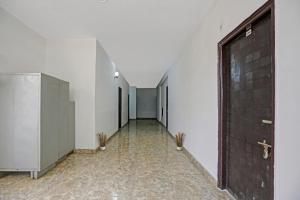 un pasillo vacío con una puerta y plantas en ella en Collection O Naveen Stay, en Gurgaon