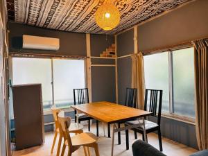 湯河原的住宿－温泉街の入り口にあるゲストハウス SLOW HOUSE yugawara，一间带木桌和椅子的用餐室