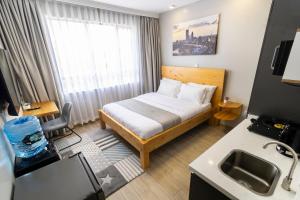 a small room with a bed and a sink at JKIA Cosy Apartments by Away Homes Rentals Ltd in Nairobi