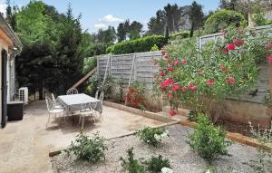 einen Garten mit einem Tisch, Stühlen und Blumen in der Unterkunft La Villa De Maussane in Maussane-les-Alpilles