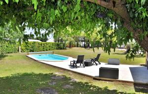 un patio trasero con piscina, 2 sillas y un árbol en La Villa Des Songes, en Pernes-les-Fontaines