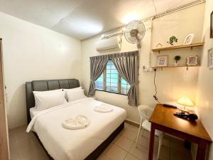 a small room with a bed and a desk and a fan at K Inn 55 in George Town