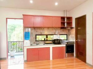 a kitchen with red cabinets and a large window at Secluded Apartment with Full Kitchen & Balcony Garden View in Liloan