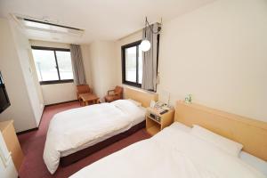 奄美市にある奄美ポートタワーホテルのベッド2台とテレビが備わるホテルルームです。