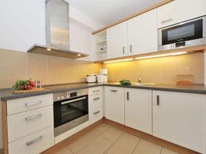 Una cocina con gabinetes blancos y un horno de estufa. en Nordic Comfortable holiday residence, en Bansin