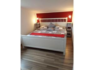a bedroom with a white bed with a red headboard at Tacke 2 Comfortable holiday residence in Burg auf Fehmarn