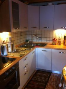 a kitchen with white cabinets and a sink at Appartamento Ivo in Campitello di Fassa