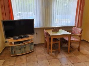 ein Wohnzimmer mit Fernseher und Tisch mit Stühlen in der Unterkunft House Neeltje, Apartment 1 in Borkum