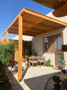 un patio con una pérgola de madera y una mesa en Little house on the prairie en Zuqim
