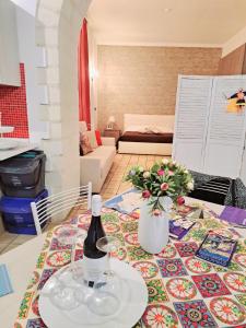 Appartamento Dammuso Isola Di Ortigia في سيراكوزا: زجاجة من النبيذ و إناء من الزهور على طاولة