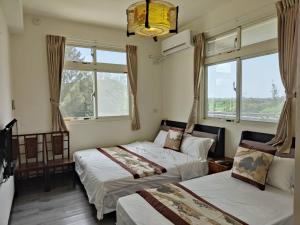 1 dormitorio con 2 camas y 2 ventanas en 金門馨紫晶民宿, en Jinning