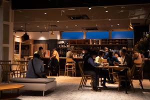 a group of people sitting at tables in a restaurant at métisse stay in Nanto