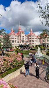 a group of people standing in front of a large building at Romantic Room - Studio Jardin - Proche Disneyland Paris in Crecy la Chapelle