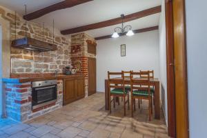 eine Küche mit einem Tisch, Stühlen und einer Steinmauer in der Unterkunft Apartmani Vugec in Betina