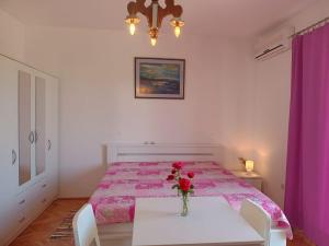 a bedroom with a bed and a table with flowers on it at Apartments Nela in Jelsa