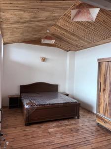 a bedroom with a bed and a wooden ceiling at Hill Billy Homes in Nāldera