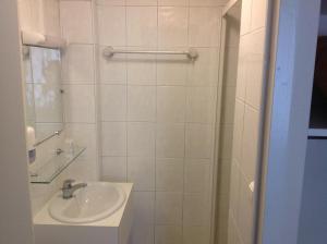 a white bathroom with a sink and a shower at Hotel de la Paix in Caen