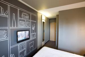 Un dormitorio con una pared negra y TV. en ibis Saint Brieuc Yffiniac, en Yffiniac
