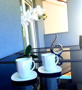 2 tasses de café blanches assises au-dessus d'une table dans l'établissement Apartments Laguna, à Nin