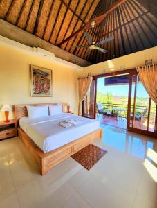 a bedroom with a large bed and a balcony at BUDA AMITABA in Ubud