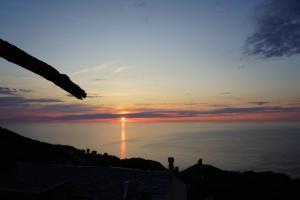 um pôr-do-sol sobre o oceano com o sol no céu em Torra di Ciocce em Pino